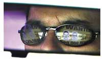 Closeup of man with wanted poster reflected in sunglasses